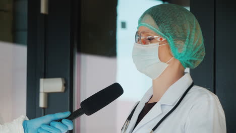 médico da una entrevista a un reportero ambos en trajes de protección