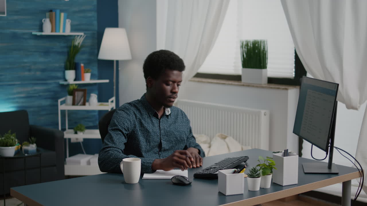 Freelancer taking notes on notepad and looking into computer