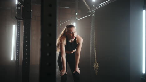 a sporty young woman pulls herself up on a horizontal bar in a dark gym in a beautiful neon backlight. endurance and perseverance in pulling up movement towards the goal