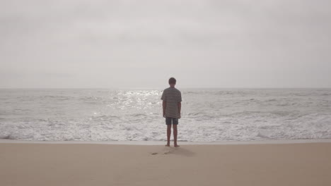 boy standing on beach at ocean