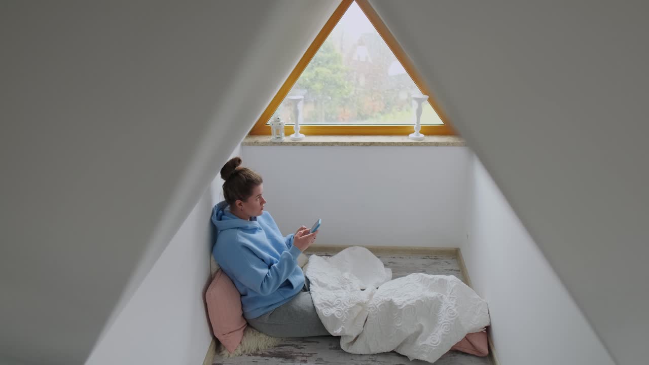 Woman using phone in an attic room