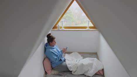 woman using phone in an attic room