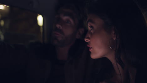 una pareja en un coche por la noche mirando un teléfono