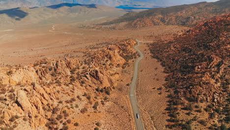 transport on the highway passing between the craggy mountains. sunlit panorama of nevada mountainous landscape on sunny day. top view.