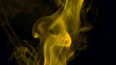 clouds of yellow smoke slowly rising graceful twists upward. colored smoke blowing from bottom to top. close-up, isolated on black background