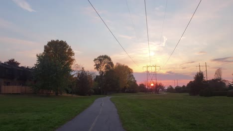 Shot-pointing-down-trees-looking-left-towards-houses-and-a-small-plane-flying-over-during-a-beautiful-sunset-near-Ottawa,Ontario