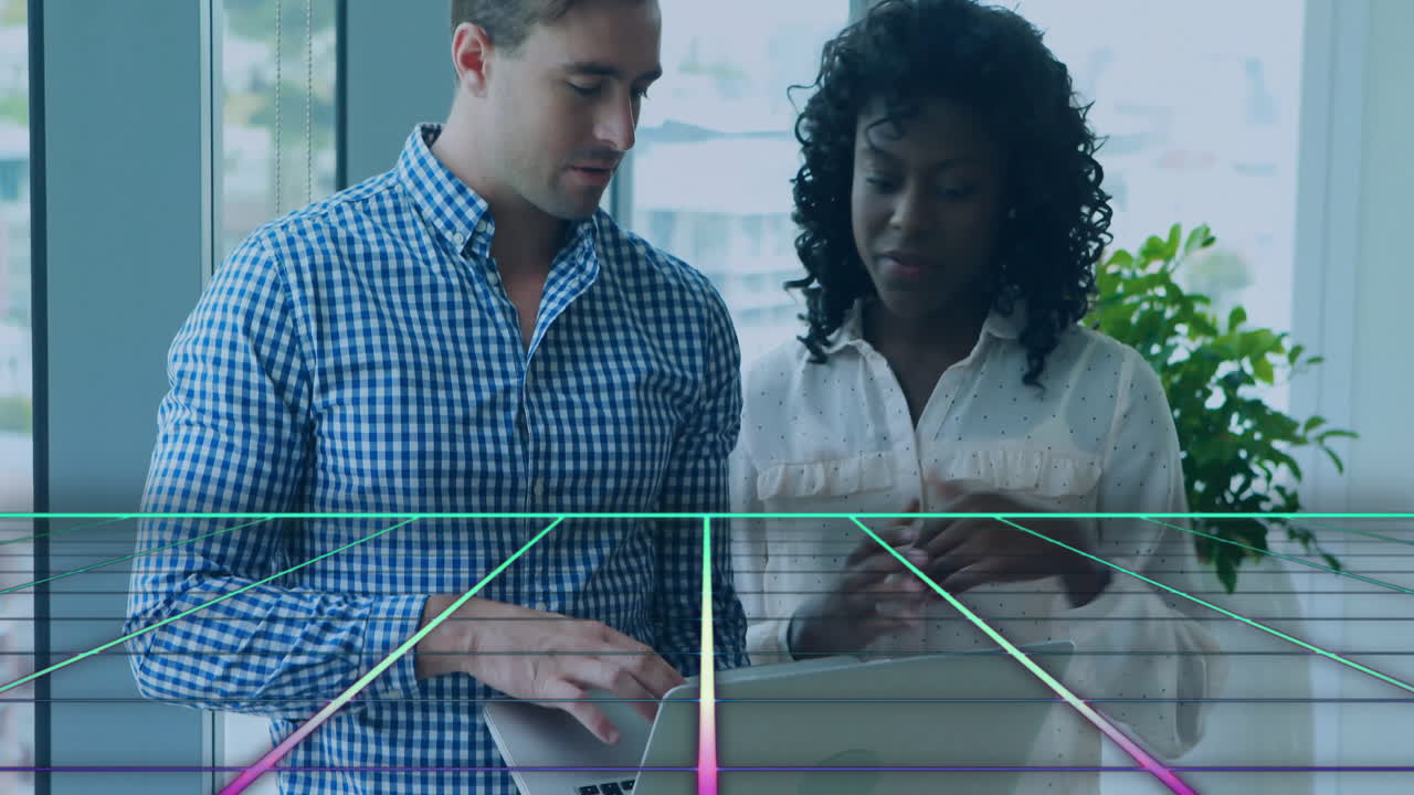 Male and female colleagues studying laptop data in office, showcasing neon grid technology overlay