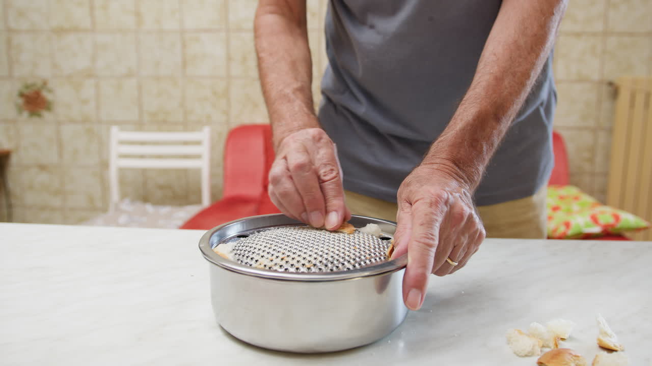 Le mani di un uomo grattugiano il pane per fare pangrattato