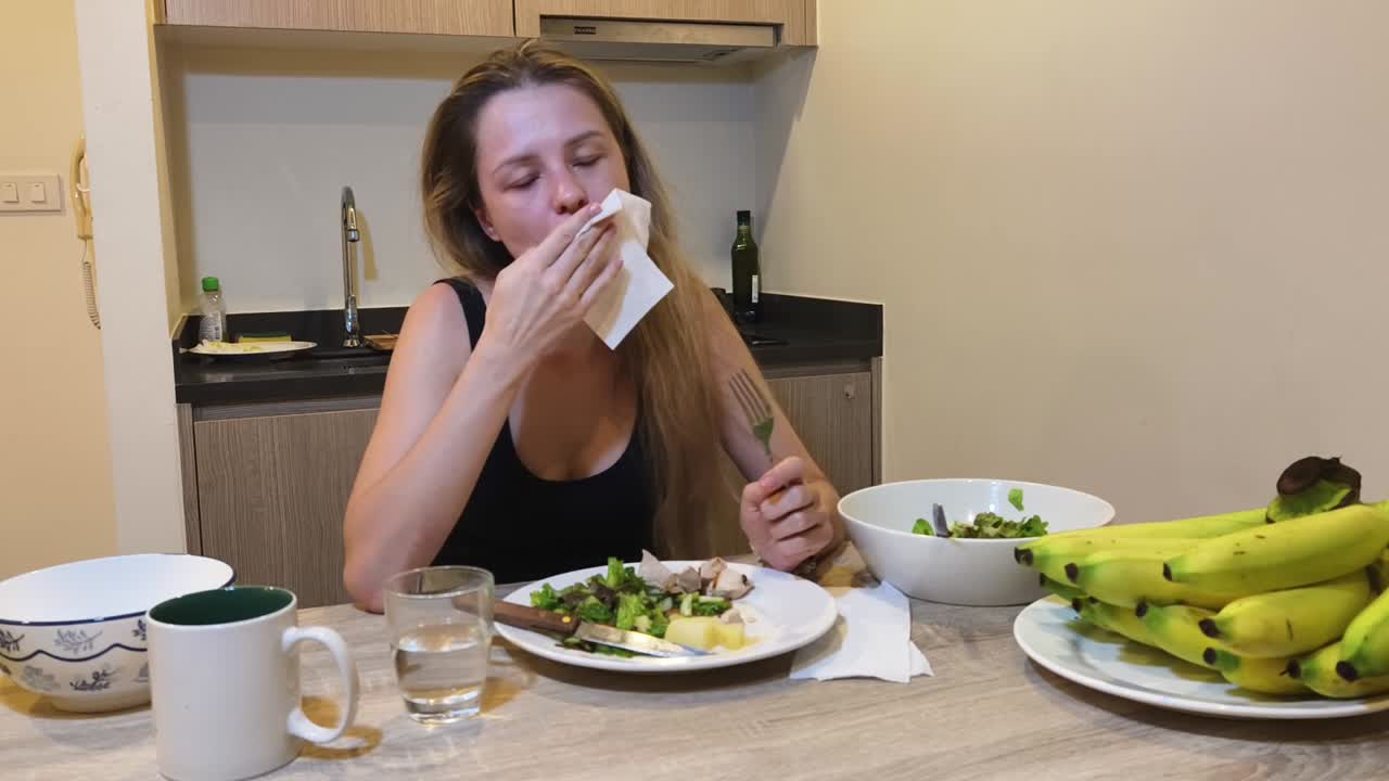 Woman eating salad and bananas at a table