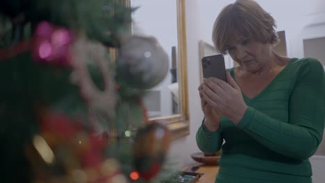 woman looking at phone near christmas tree