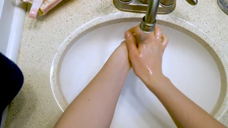slow motion female hands rinsing off over basin with water coming from faucet