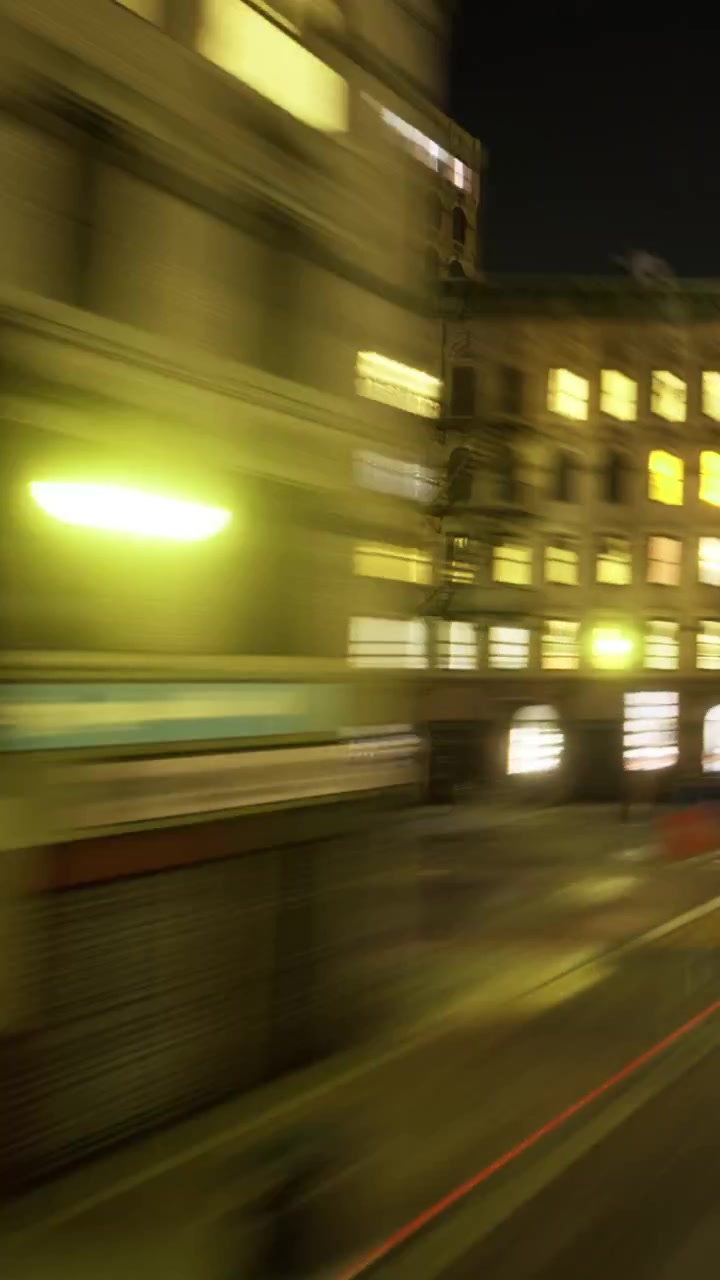Le finestre brillano in una strada cittadina di notte con movimento sfocato.