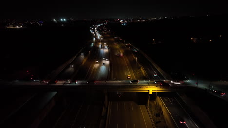 busy highway road at night with glowing vehicle lights, aerial drone view