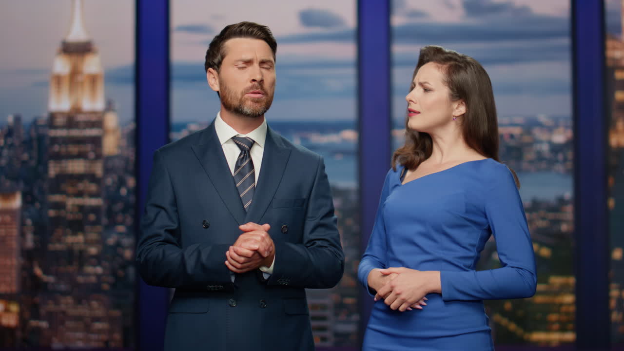 Due giornalisti che discutono le notizie in piedi sul palco di uno studio televisivo, primo piano. Coppia di conduttori.