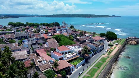 Aerial-drone-pan-of-shops-hotels-and-housing-in-Galle-old-town-fort-Dutch-history-architectural-town-with-beach-waves-Sri-Lanka-Asia-travel-tourism