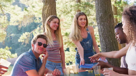 group of friends unpacking food at a picnic table by a lake