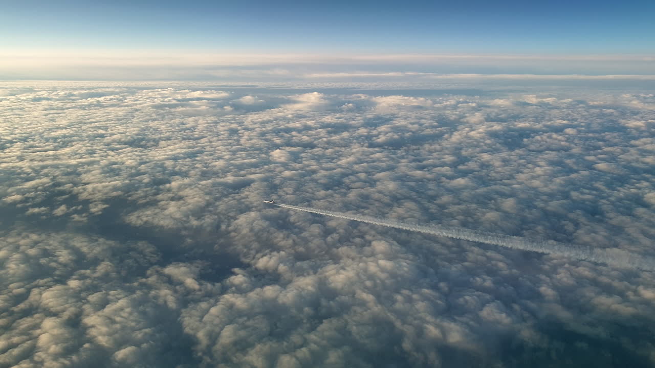 vista increíble desde la cabina de un avión que vuela alto por encima de las nubes dejando un largo rastro de aire de vapor de condensación blanco en el cielo azul