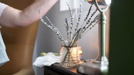 woman is arranging stems of lavender flower in a vase, household decoration concept