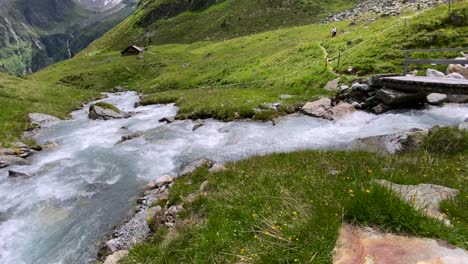 gimbal walk about a wooden footbridge accross a wild river in the beautiful lüsens valley in austria with high mountains in the background