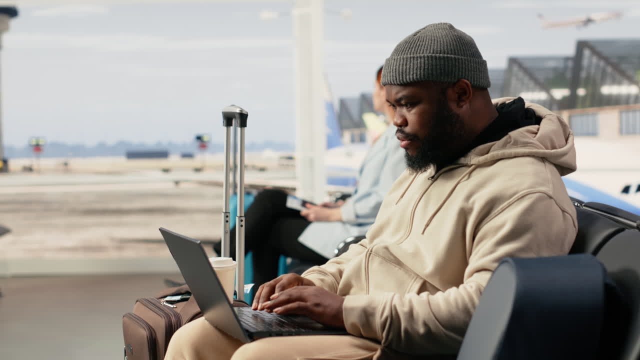 Uomo felice che lavora al laptop e beve caffè in aeroporto