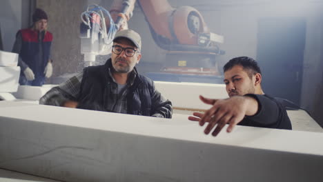 industrial foam cutting process with robotic arm and workers