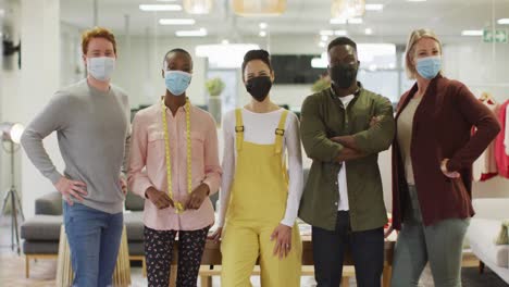 diverse group of male and female business colleagues wearing face masks and looking at camera