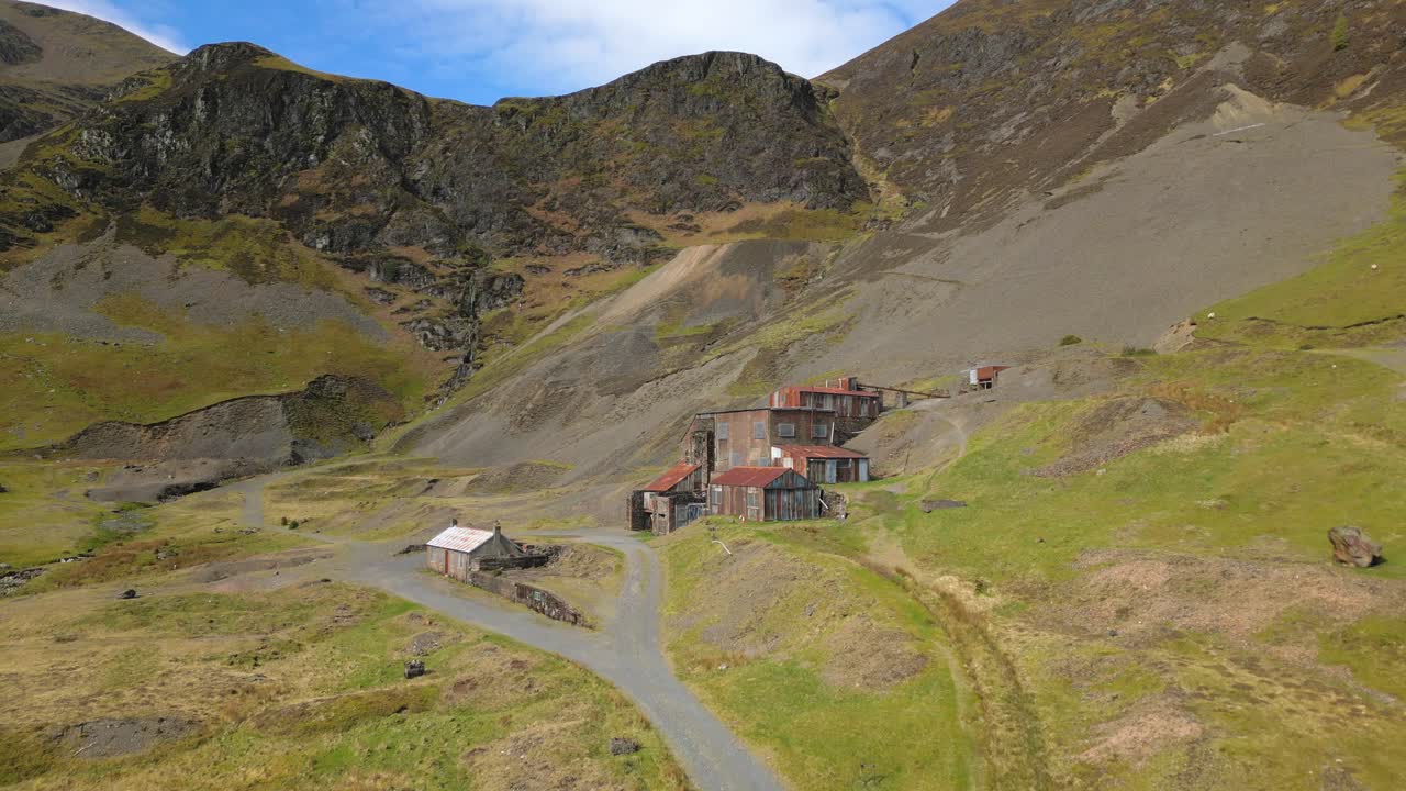 excursionistas caminando hacia viejos edificios abandonados en la mina force crag coledale beck en el distrito de los lagos ingleses