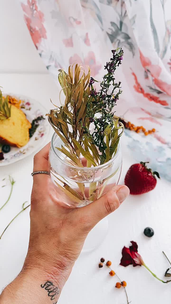 Hand Holding Glass with Dried Flowers and Fruits