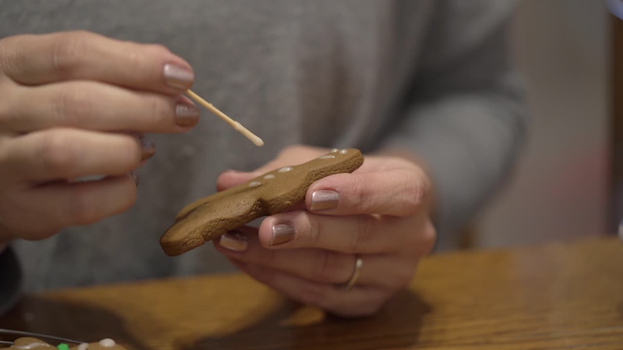Close-up shot of a lady putting icing on a gingerbread man