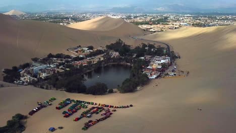 aéreo, retroceder, disparo de drones, alejándose del oasis y el pueblo de huacachina, en un día soleado, en el sur de perú