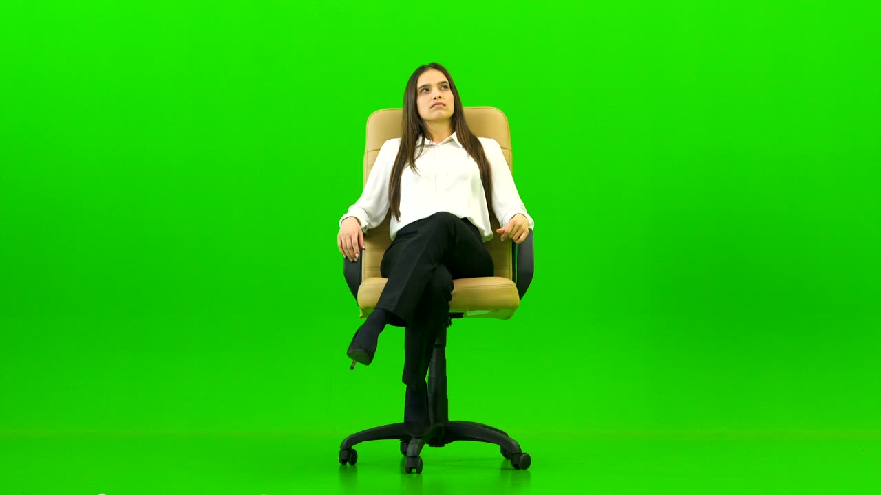 La donna sulla sedia da ufficio che parla sullo sfondo verde