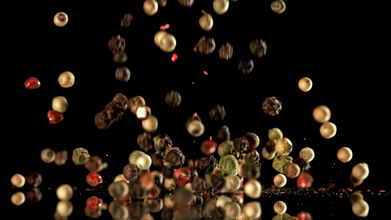 Mixed Peppercorns Falling in Slow Motion on Reflective Black Surface