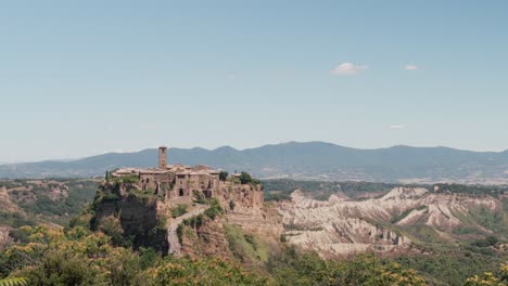 tourists walk the path up to the ancient village of civita di bagnoregio, also known as "the dying city", in italy