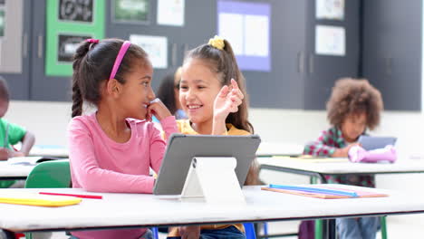 in school, two girls using tablet and smiling in classroom, enjoying learning