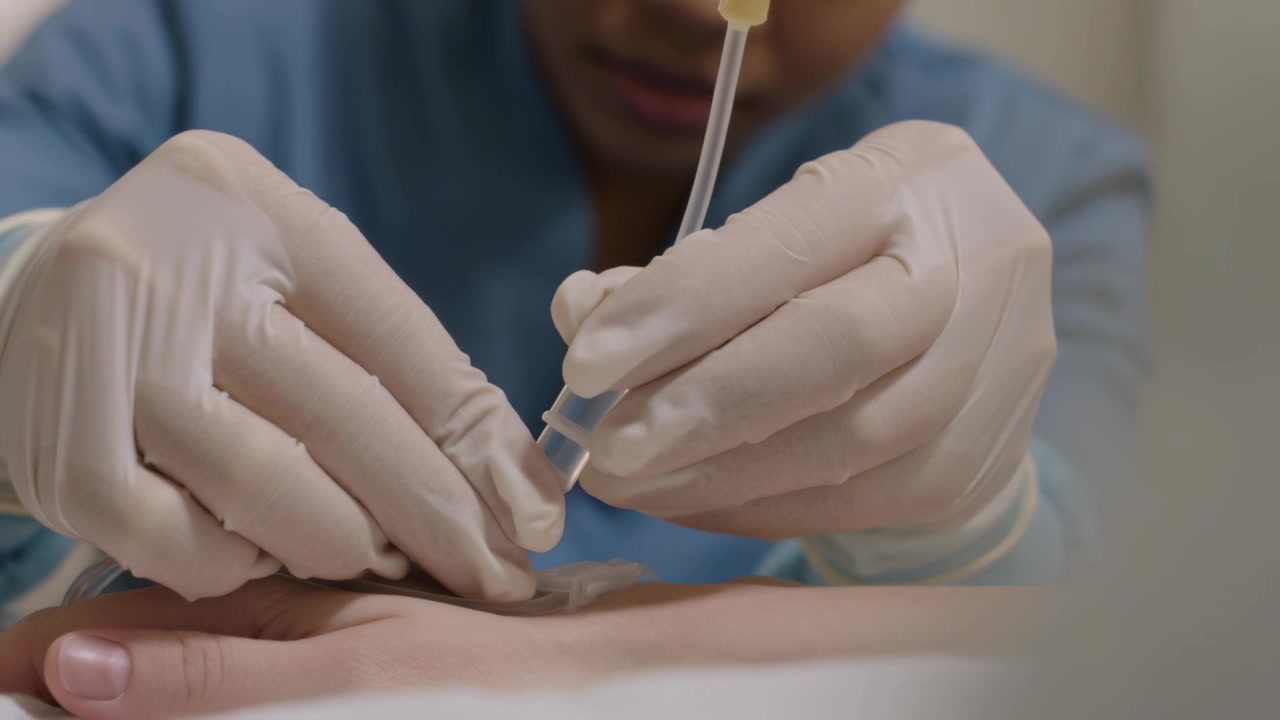 Osservando il raccordo che collega un'infermiera guantata in divisa che allinea il tubicino della flebo sulla mano in clinica, preparando il flusso.