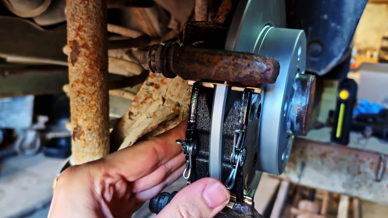 Mechanic fits new brake pads onto new brake disk during brake replacement process