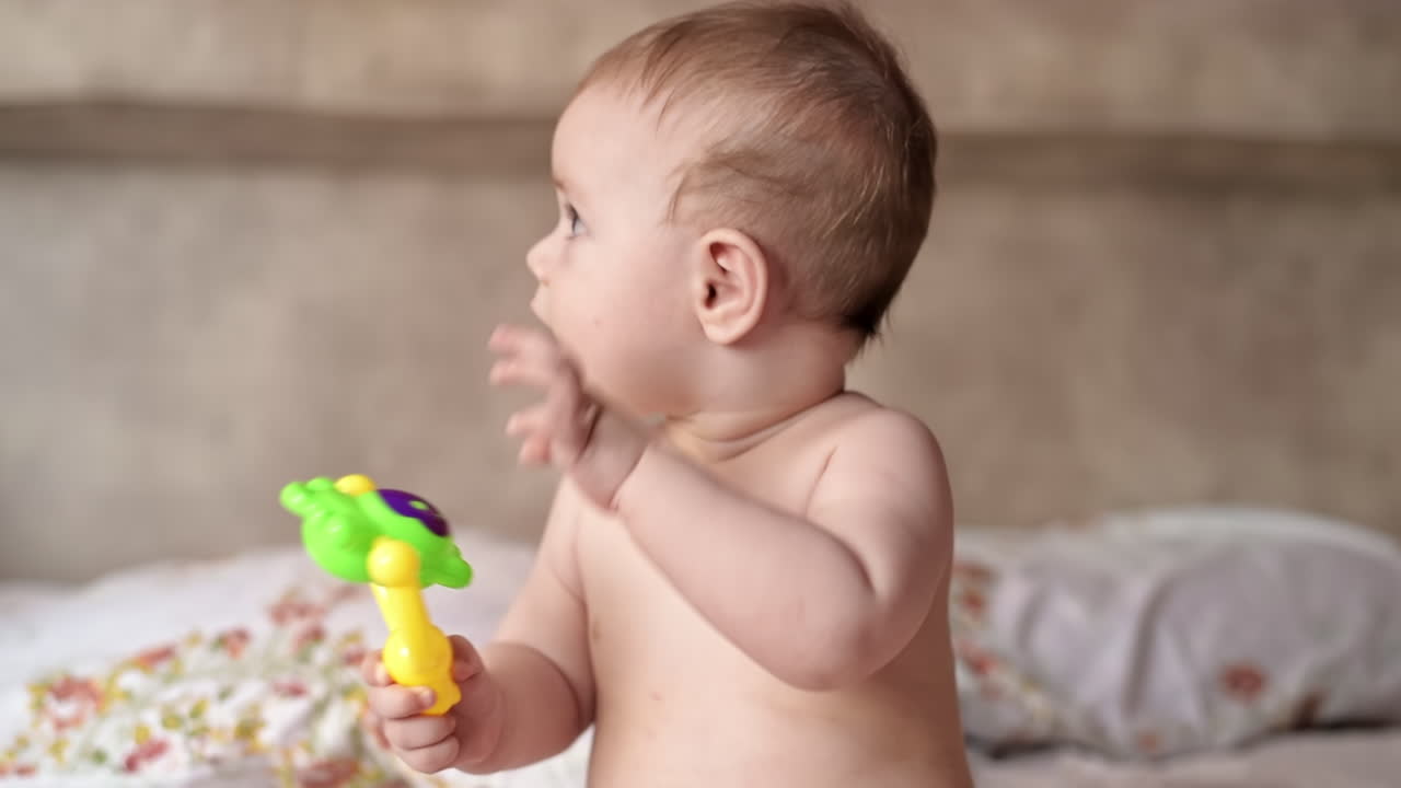 Caucasian blonde baby boy on a bed with toys
