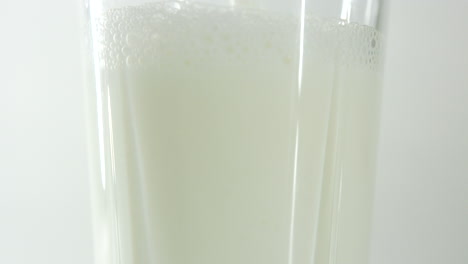 milk being poured into a glass showing just the middle section of the glass in close-up