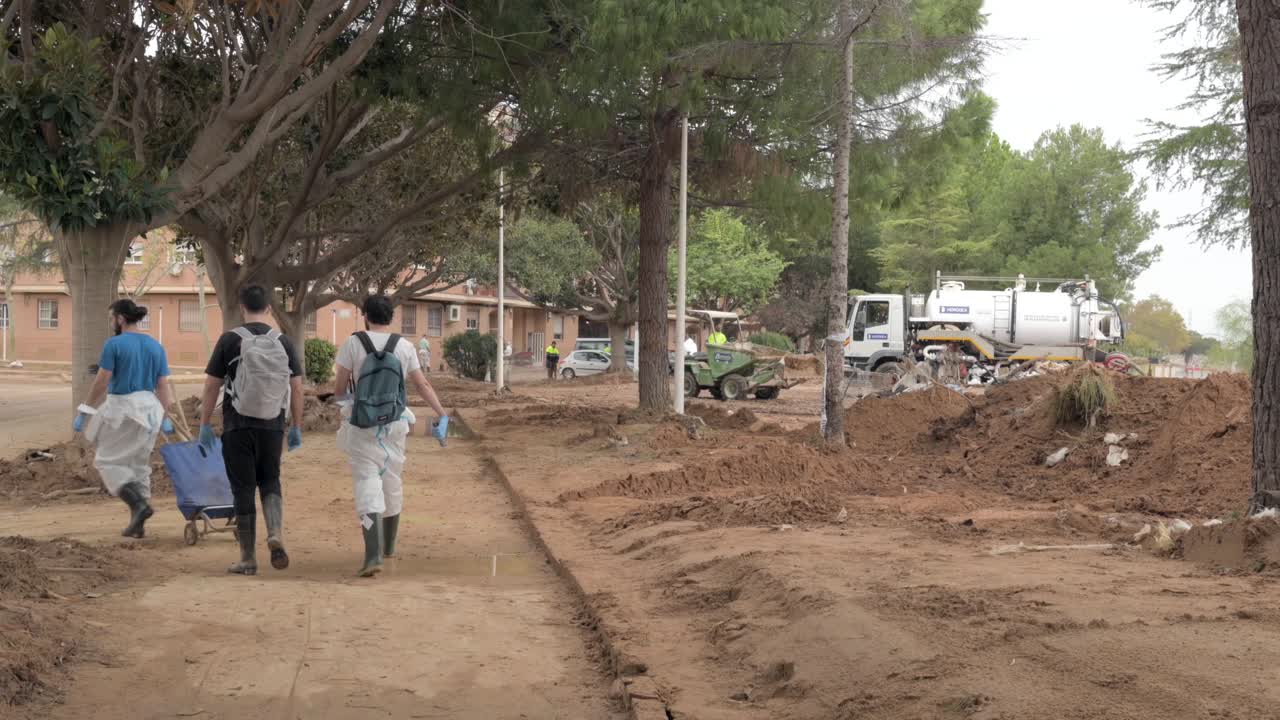 Volunteers walking through Picaña streets full of mud and debris after a flood