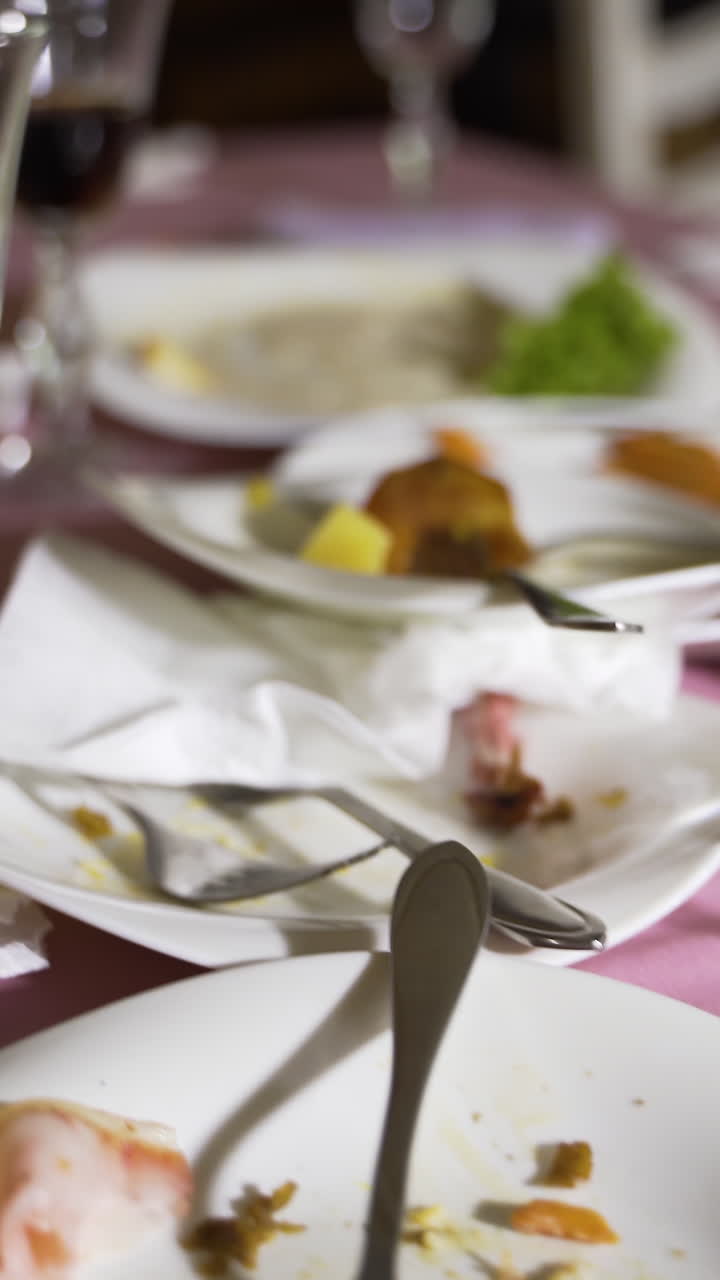 holiday table after the fun. Leftovers of food in the plates and dirty napkins are on the table. Camera motion forward Vertical video