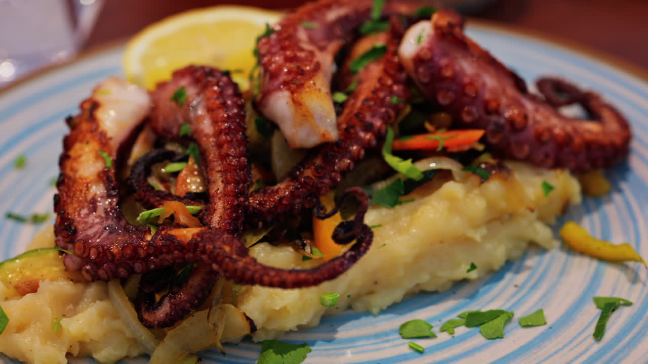 Close up of grilled octopus on a puree and a piece of lemon at a restaurant