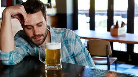 hombre triste tomando cerveza en el mostrador del bar