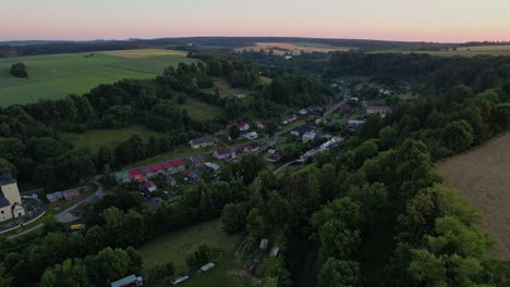 Langsamer-Drohnenflug-Am-Frühen-Abend-über-Dem-Dorf-Im-Tal-Zwischen-Den-Hügeln-Und-Der-Eisenbahn