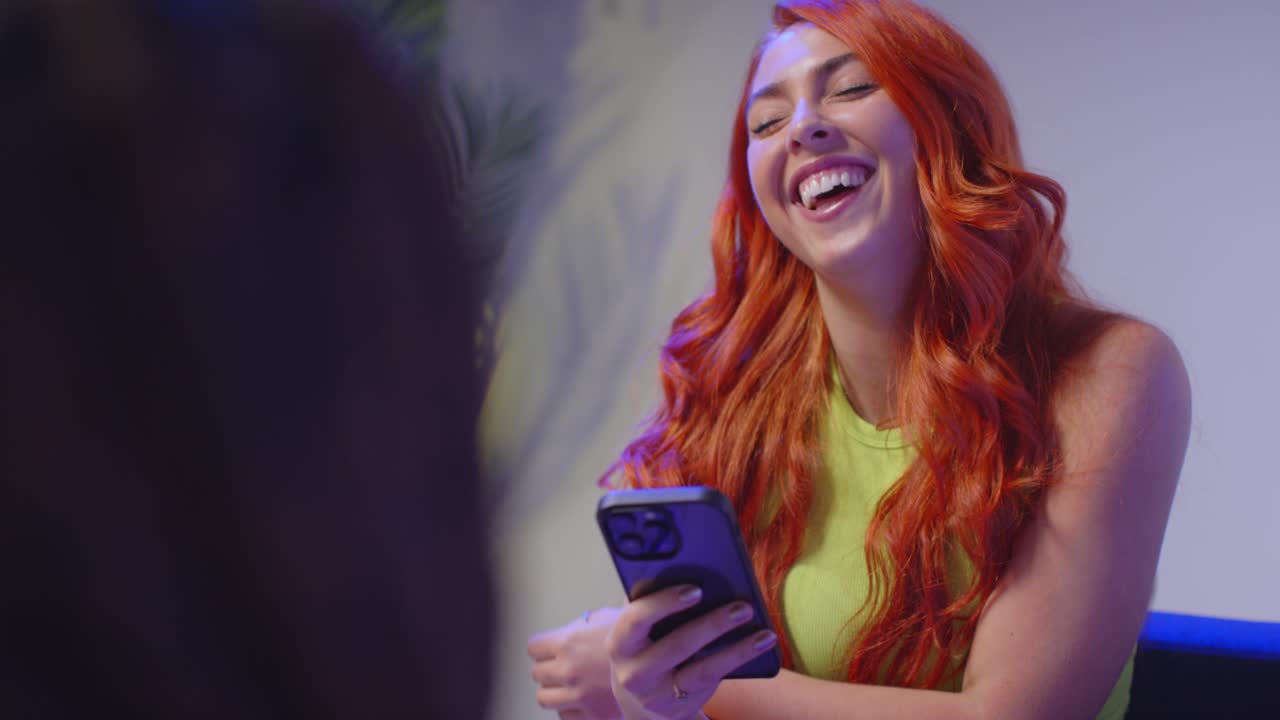 fotografía de estudio de cerca de amigos jóvenes de la generación z sentados en el sofá hablando y compartiendo publicaciones en las redes sociales en teléfonos móviles 12