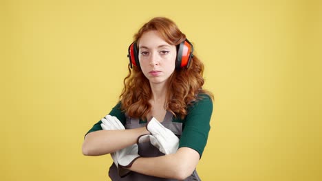 woman in workwear and earmuffs with arms crossed