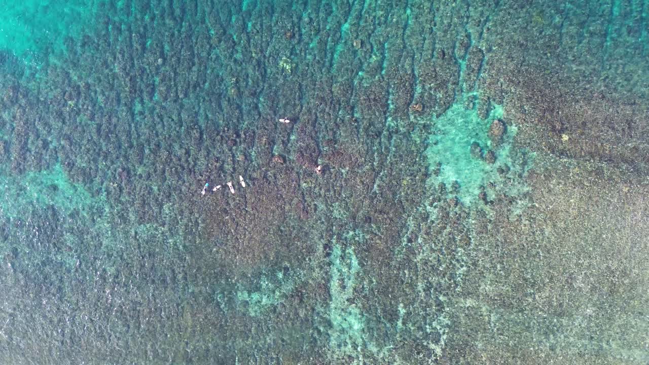 Aerial drone shot of coral reef floor with surfers waiting in line-up tropical holiday Port Vila Pango Beach Vanuatu Pacific Islands 4K