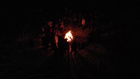 a neat perspective of people standing around a bon fire as seen from a birds eye view