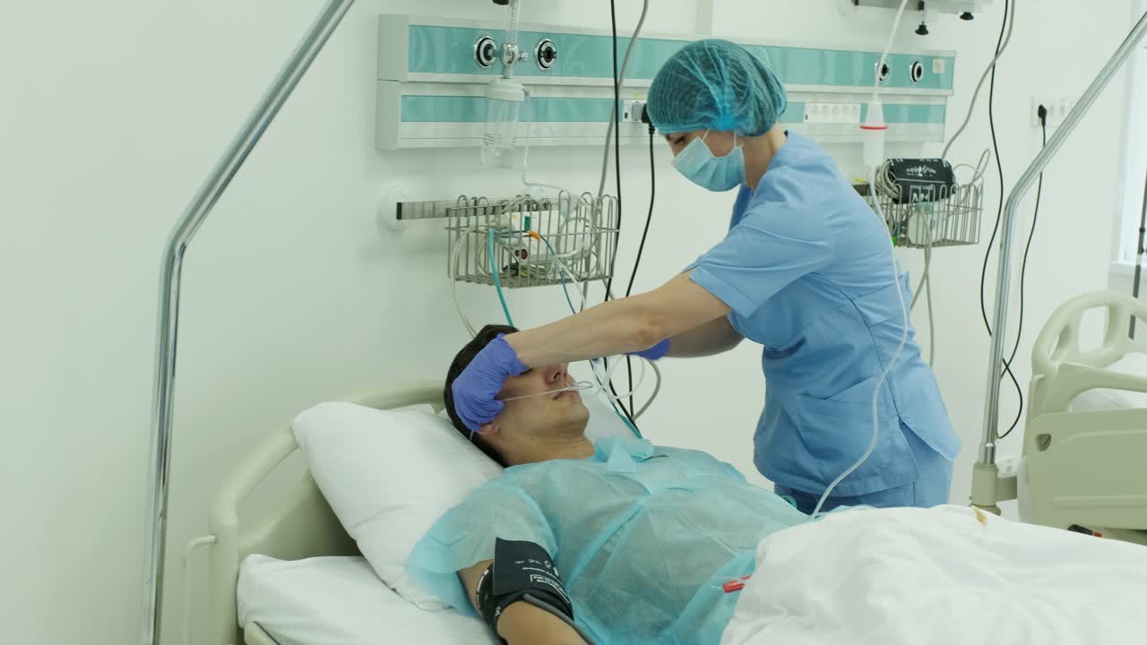 la enfermera pone la máscara de oxígeno del paciente en la unidad de cuidados intensivos.