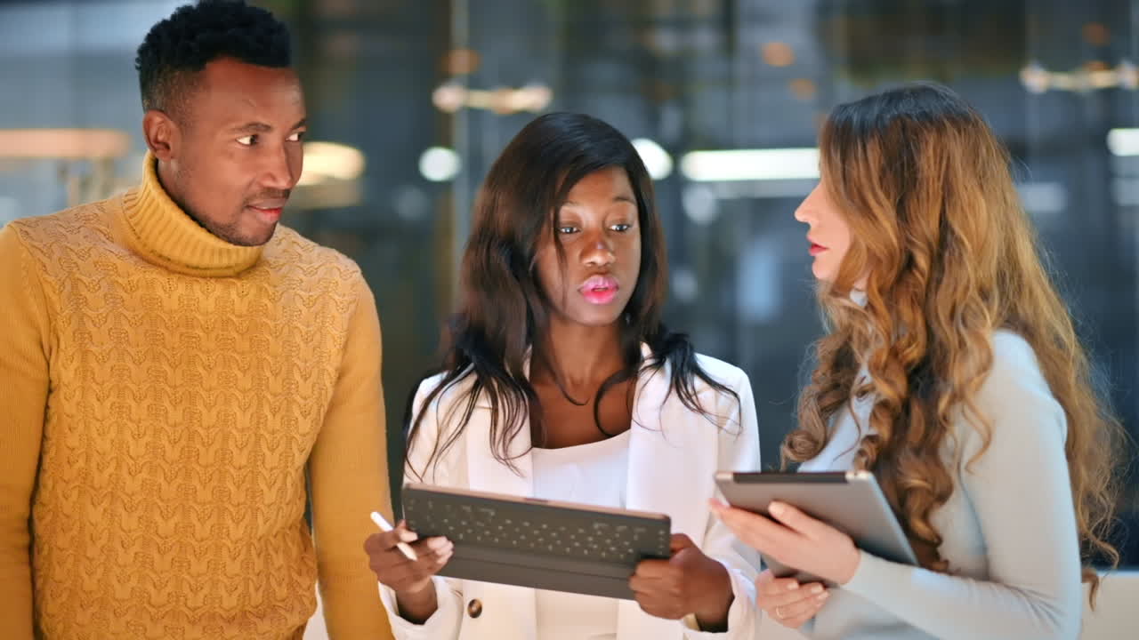 Multiracial group of workers in an office discussing business affairs using tablets. Slow motion