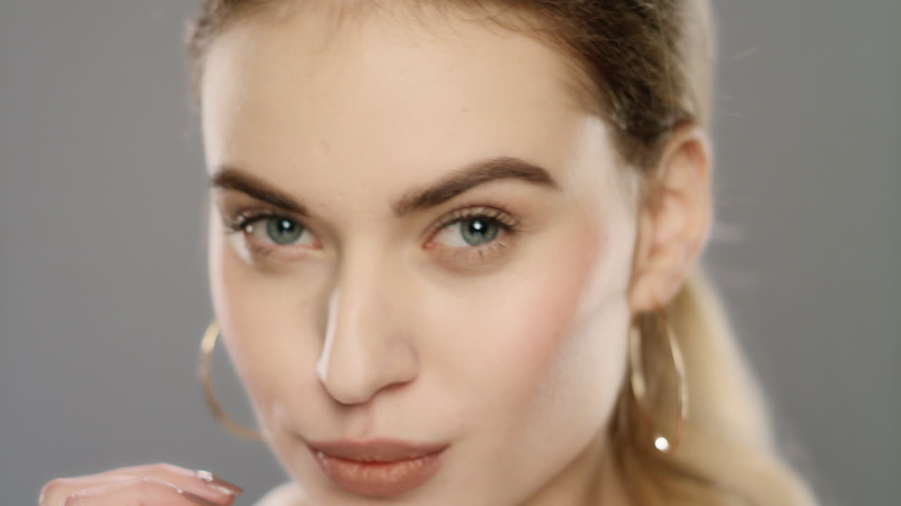 mujer joven tocando la piel de la cara en el estudio. modelo de moda corrigiendo el maquillaje